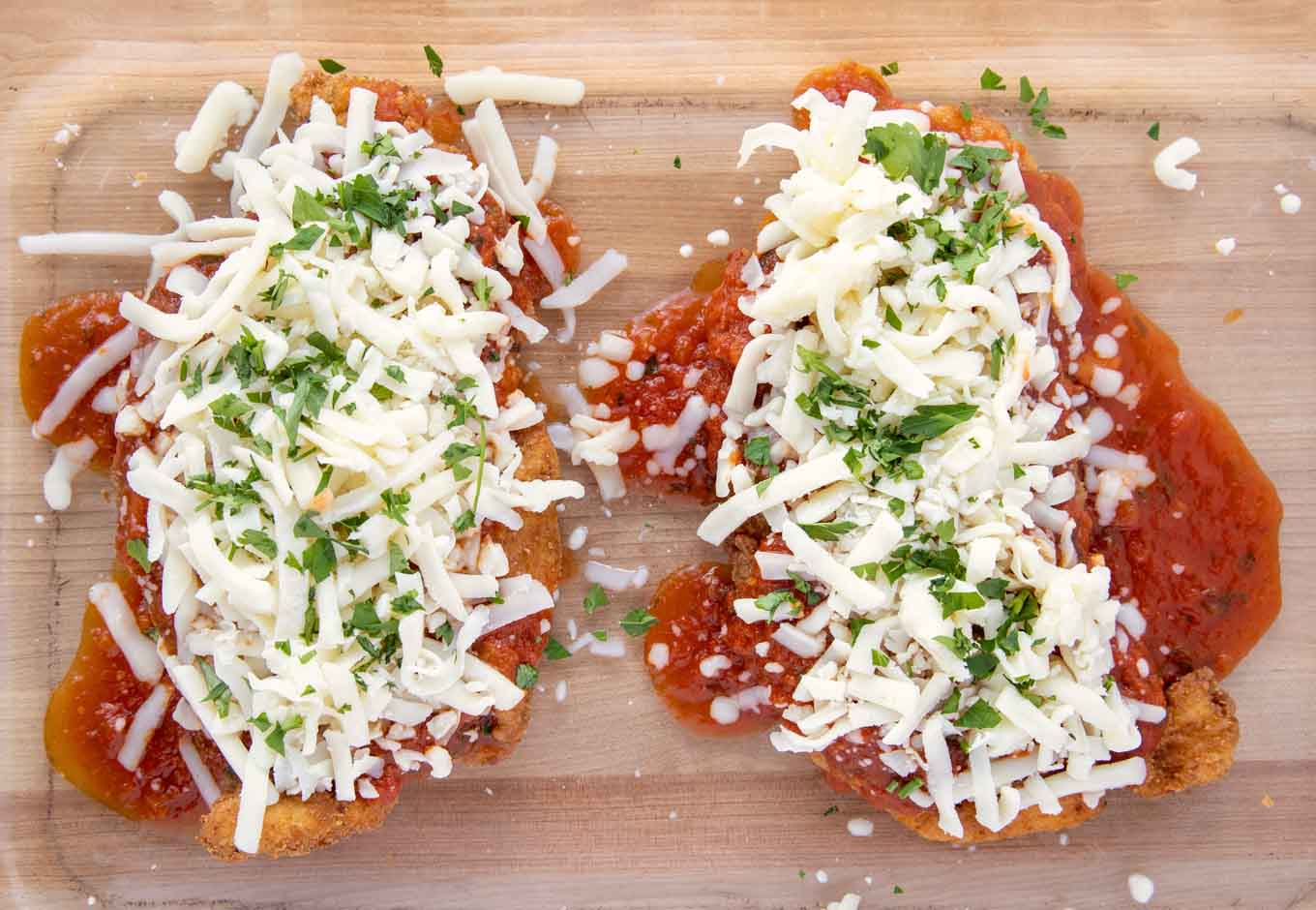 fried chicken cutlets with sauce and shredded mozzarella cheese.