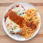 chicken parm with pasta on a white plate