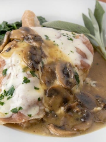 close up of chicken saltimbocca on a white plate