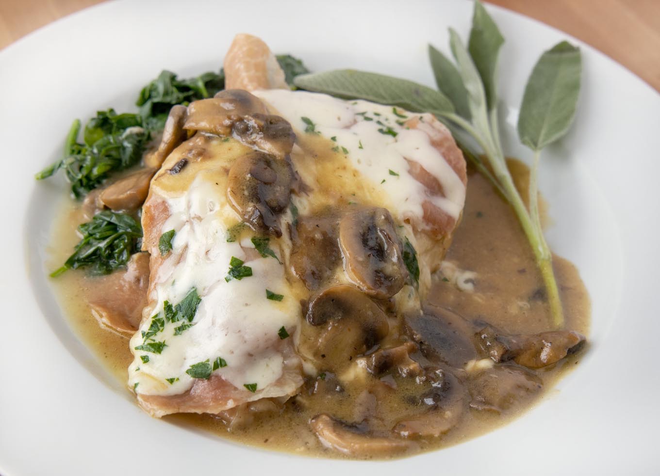 close up of chicken saltimbocca on a white plate