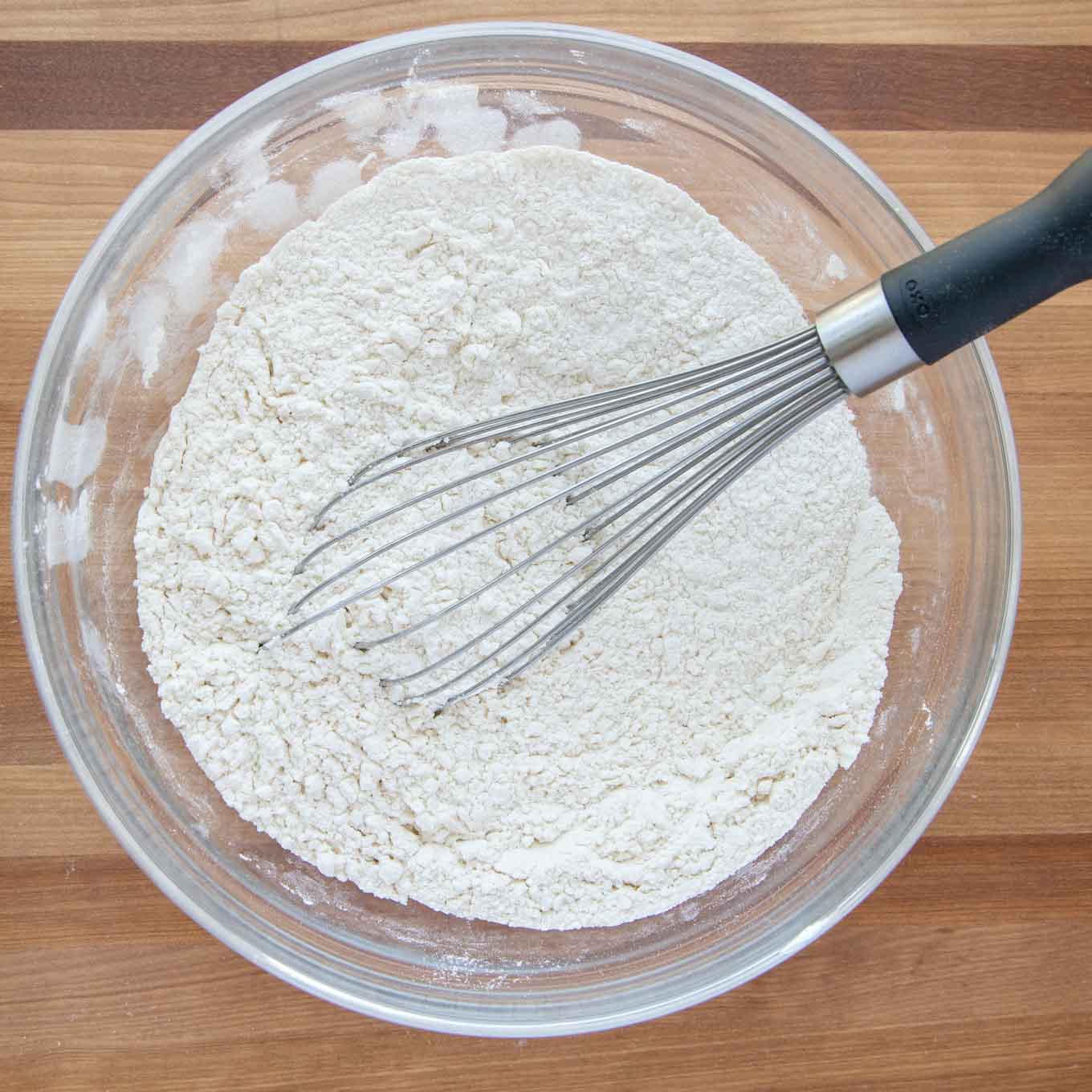 flour mixture in a glass bowl with a wire whisk in the bowl