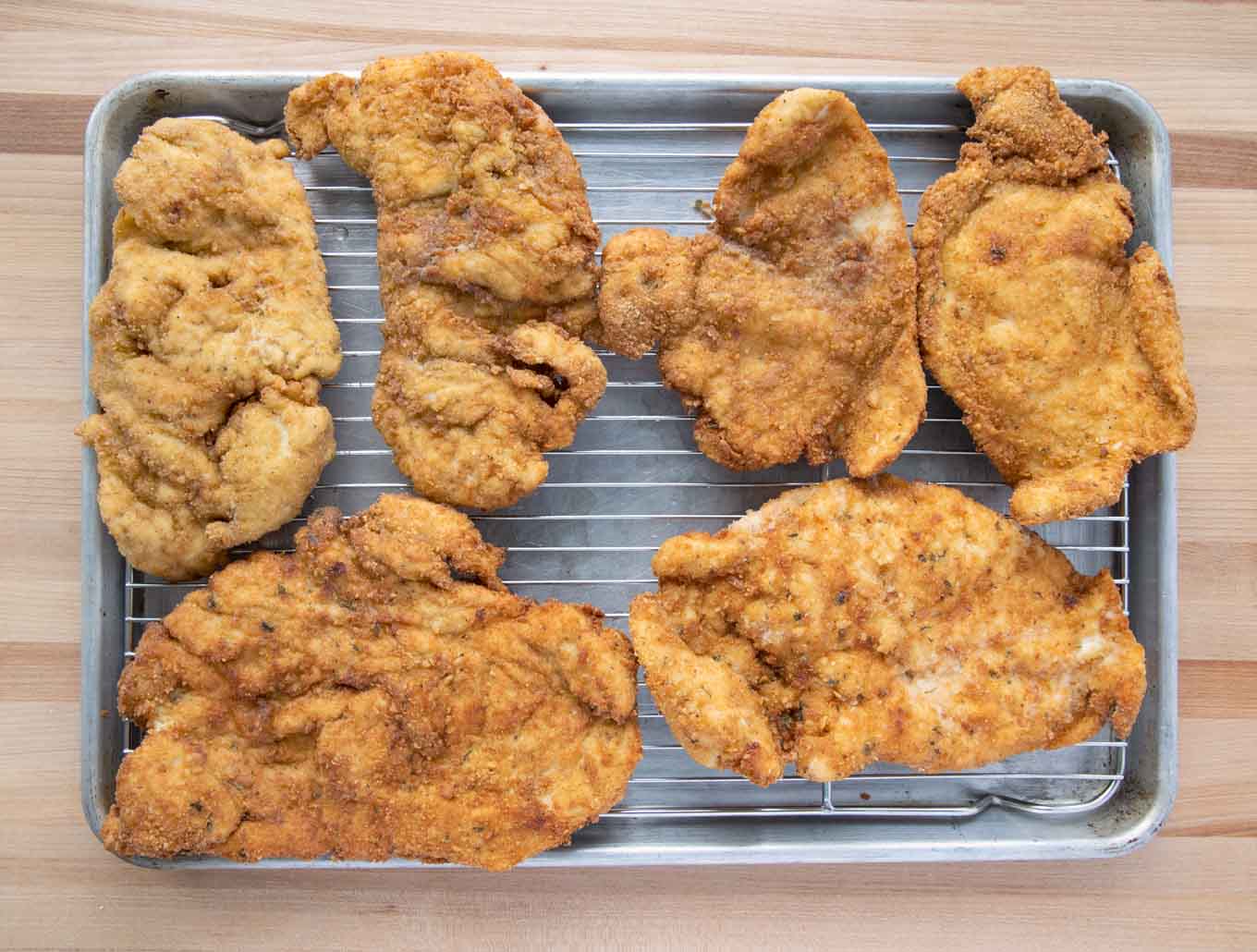 Fried chicken cutlets on a draining screen.