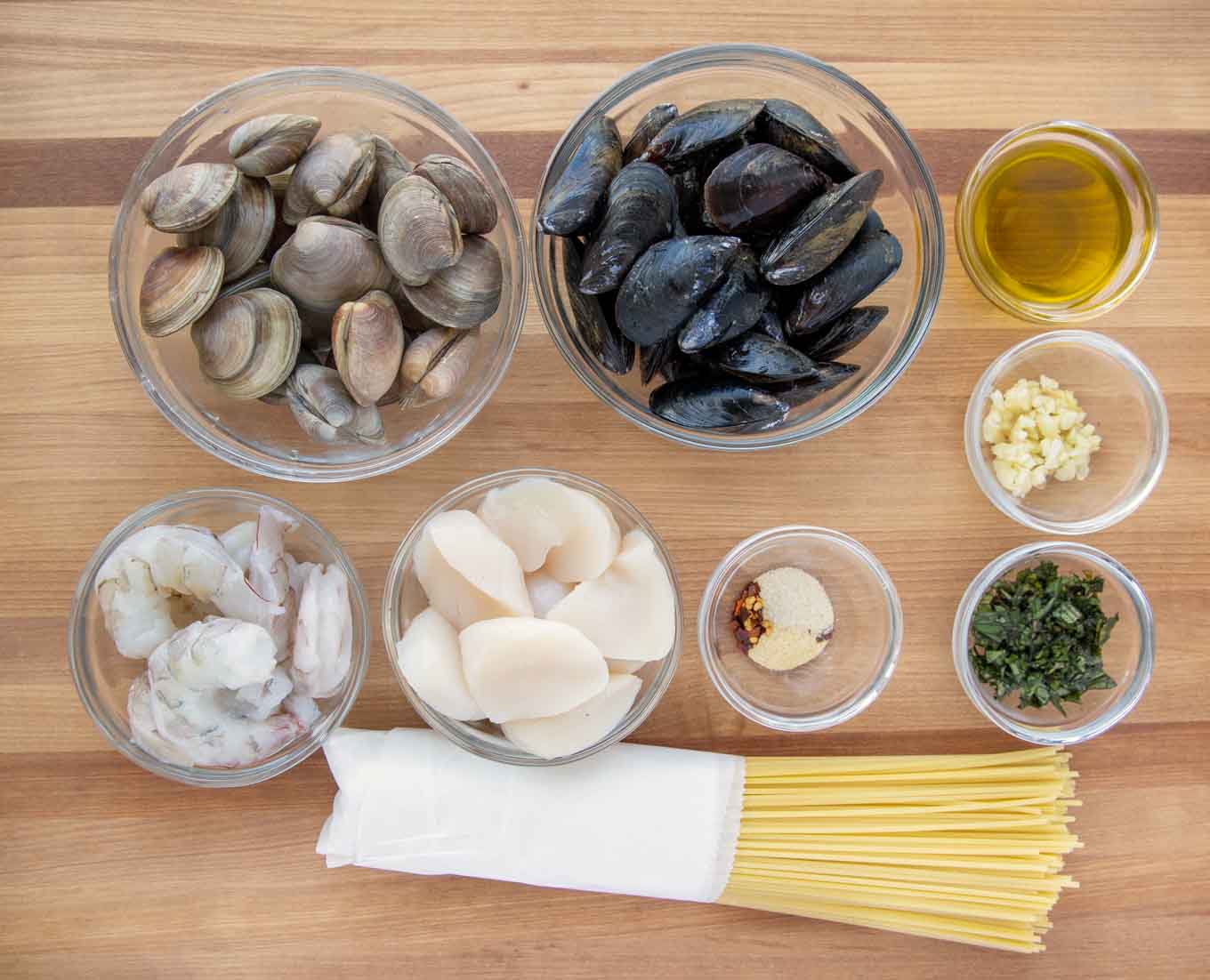ingredients to make frutta di mare in glass bowls on a wooden cutting board