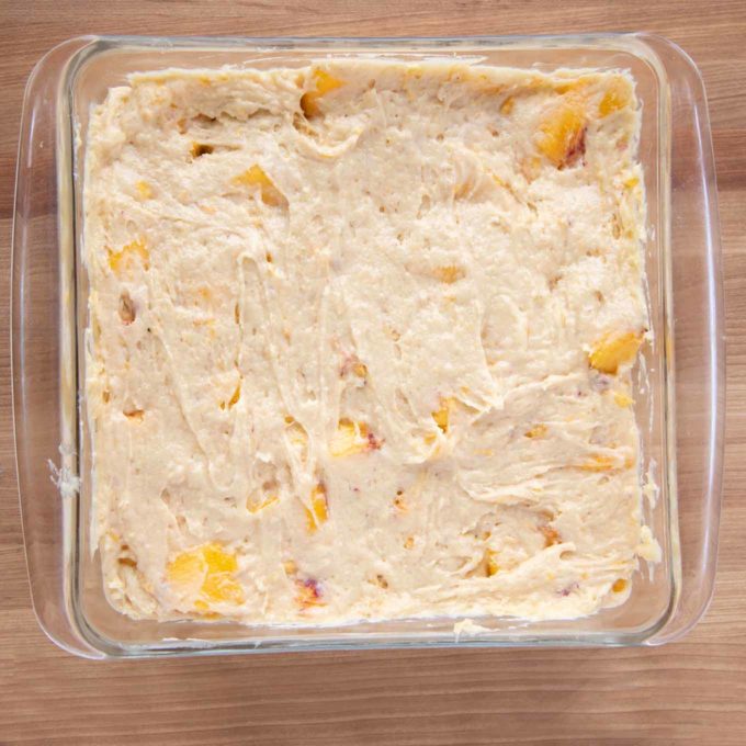 peach buckle batter in a nine inch square glass baking dish