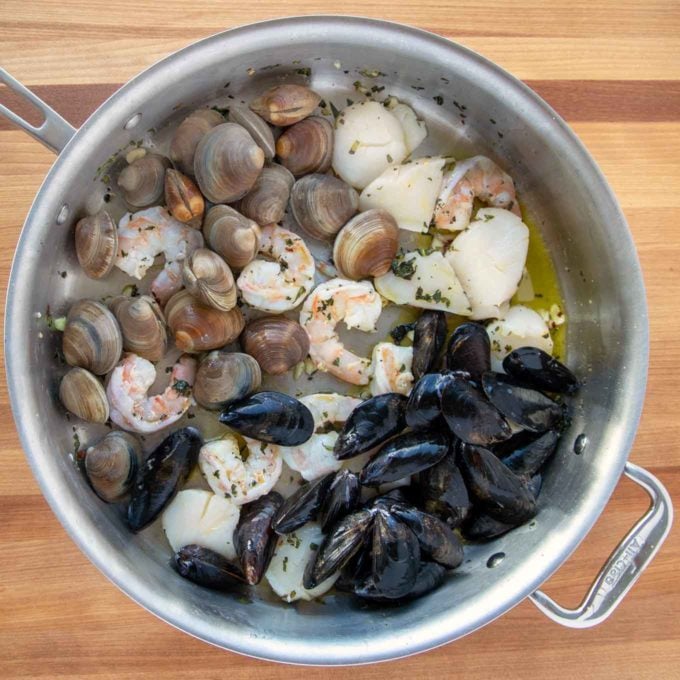 uncooked seafood in large saute pan