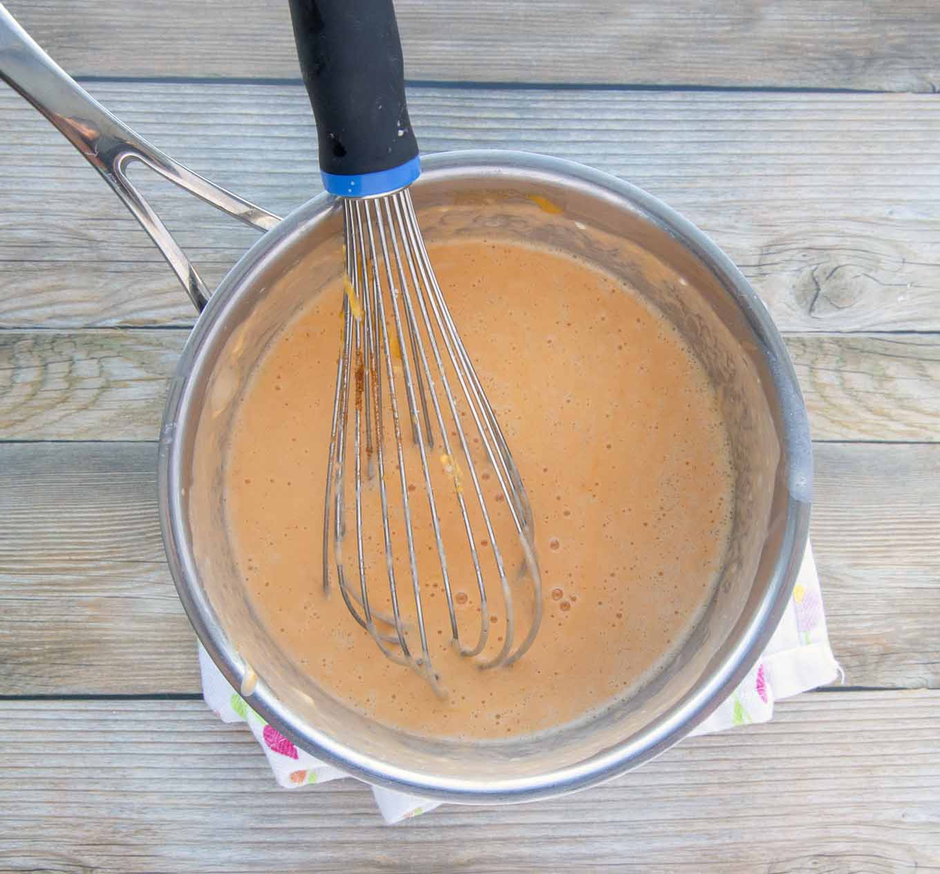 cheese sauce in pot with a wire whisk