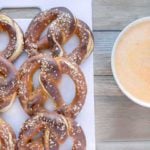 beer pretzels on a white tray with a bowl of cheddar sauce next to it
