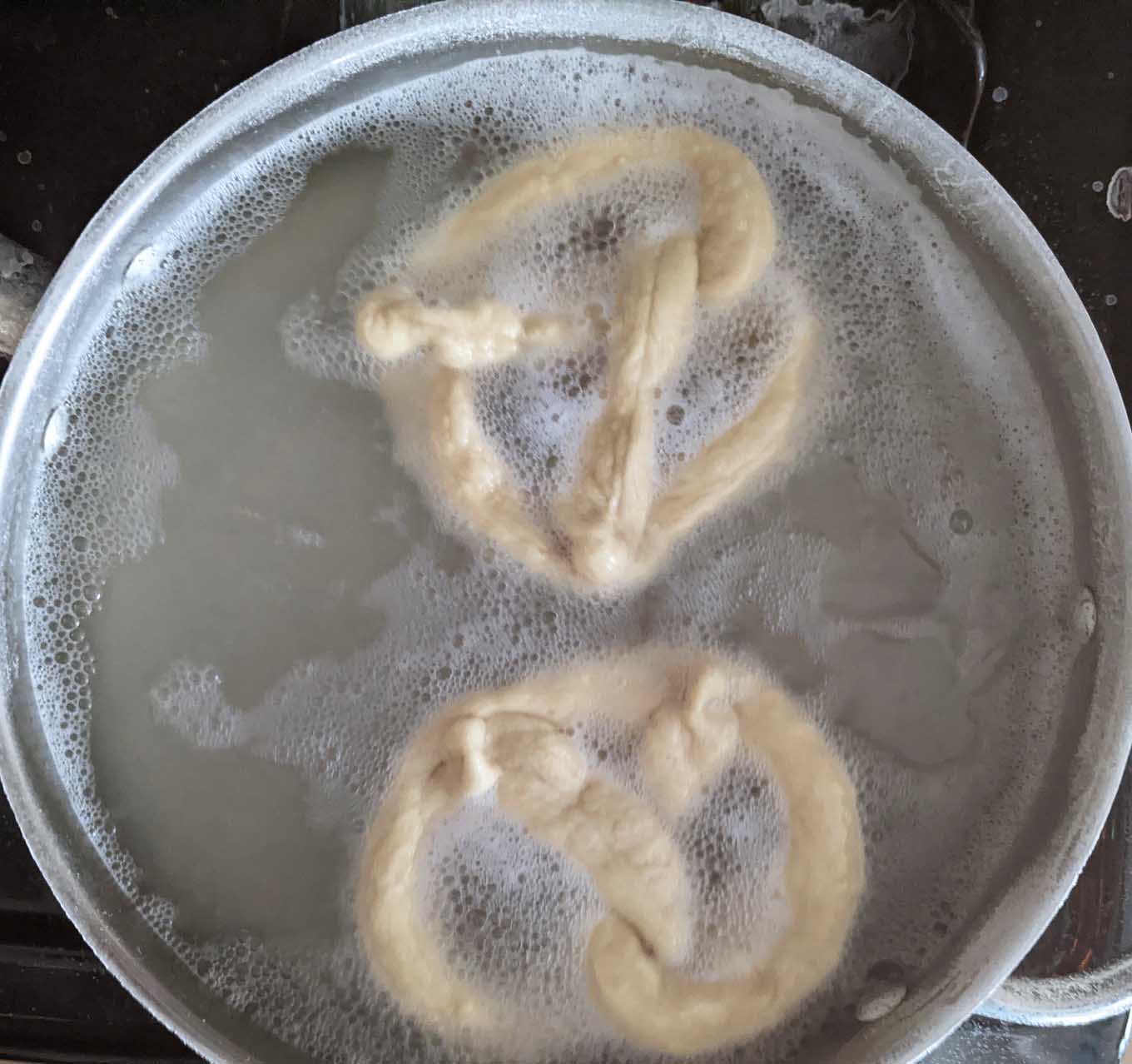 raw pretzels in a pot of boiling water 