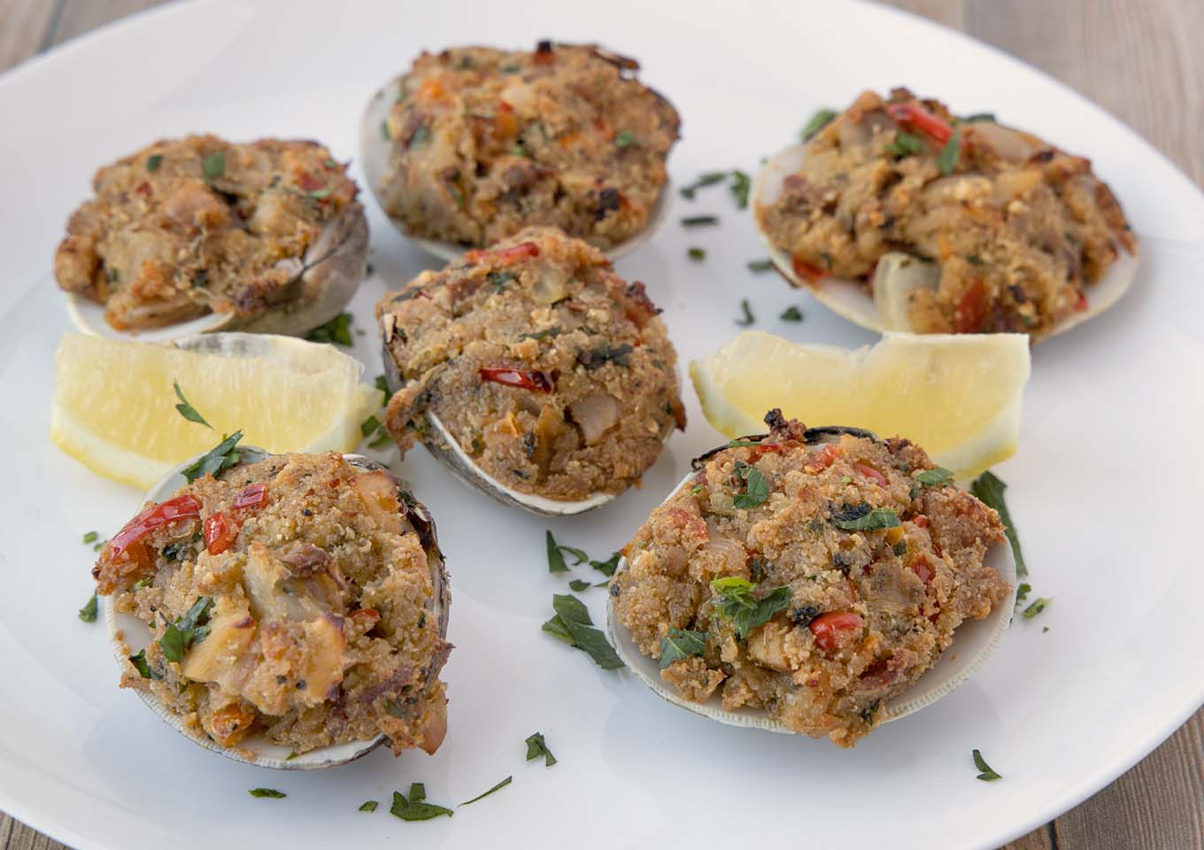 baked stuffed clams on a white plate with lemon wedges