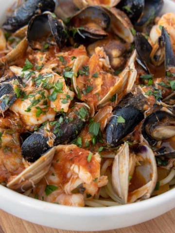 seafood marinara over pasta in a white bowl