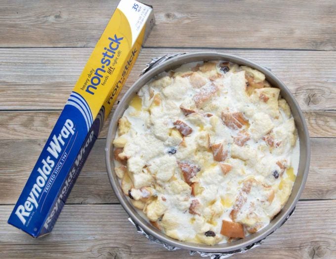 bread pudding topped with cream and melted butter next to a box of foil