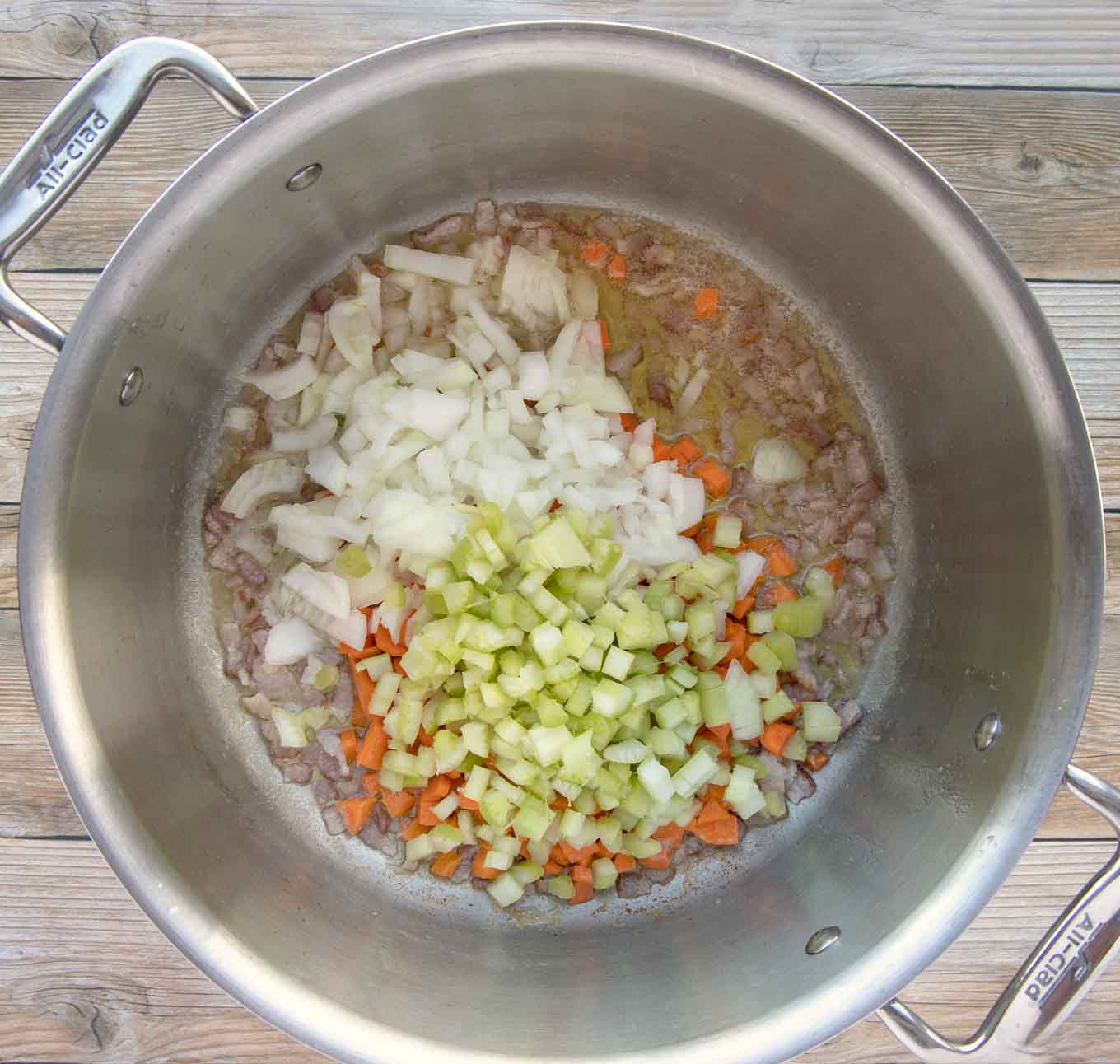 pot with onions, carrots and celery added to cooked bacon