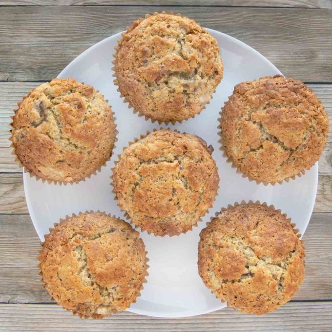 six banana pecan muffins on a white plate