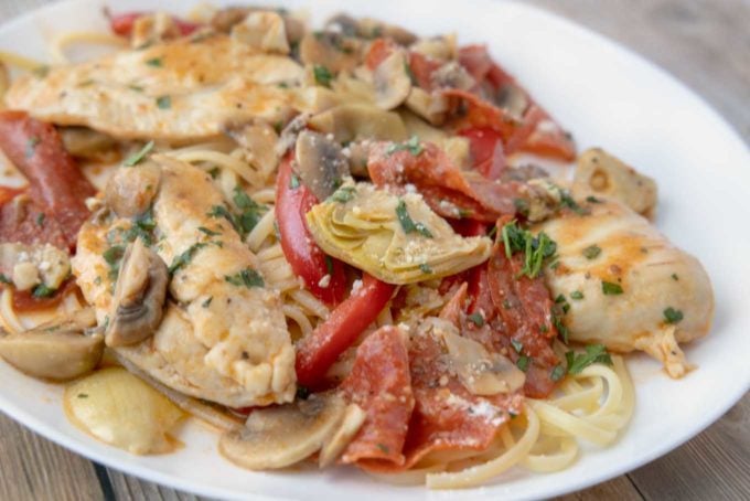 chicken pepperoni over linguine on a white plate