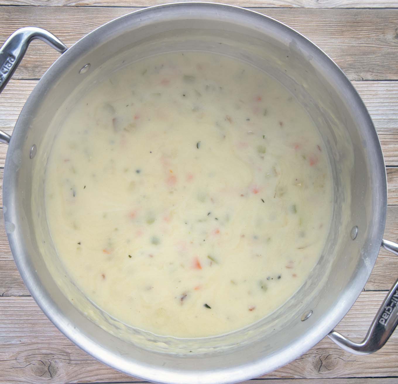 new england clam chowder in large pot with milk added