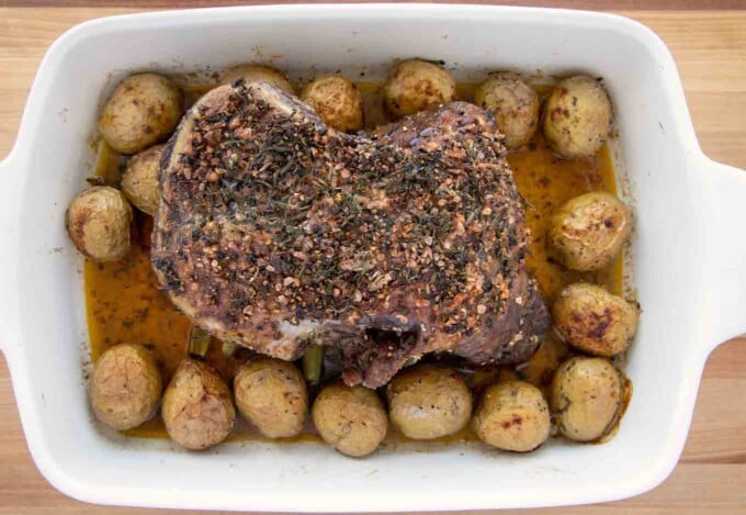 roasted leg of lamb and potatoes in a baking dish