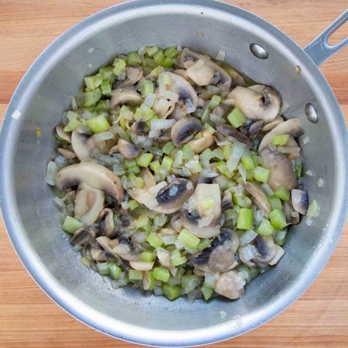 celery, onions and mushrooms cooking in melted butter in a saucepan