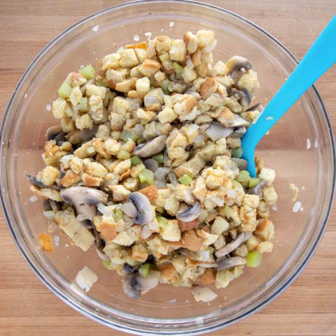 stuffing mixed in a glass bowl with a blue silicone spatula