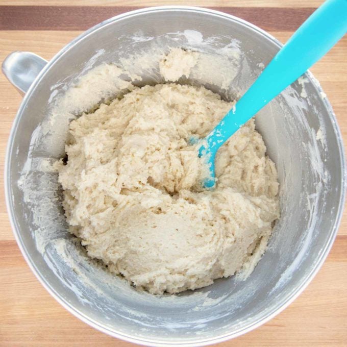 finished ricotta cookie dough in a stand mixer bowl with a blue rubber spatula in the dough