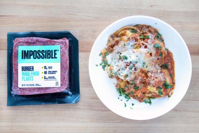 ravioli lasagna on a white plate next to a package of impossible burger