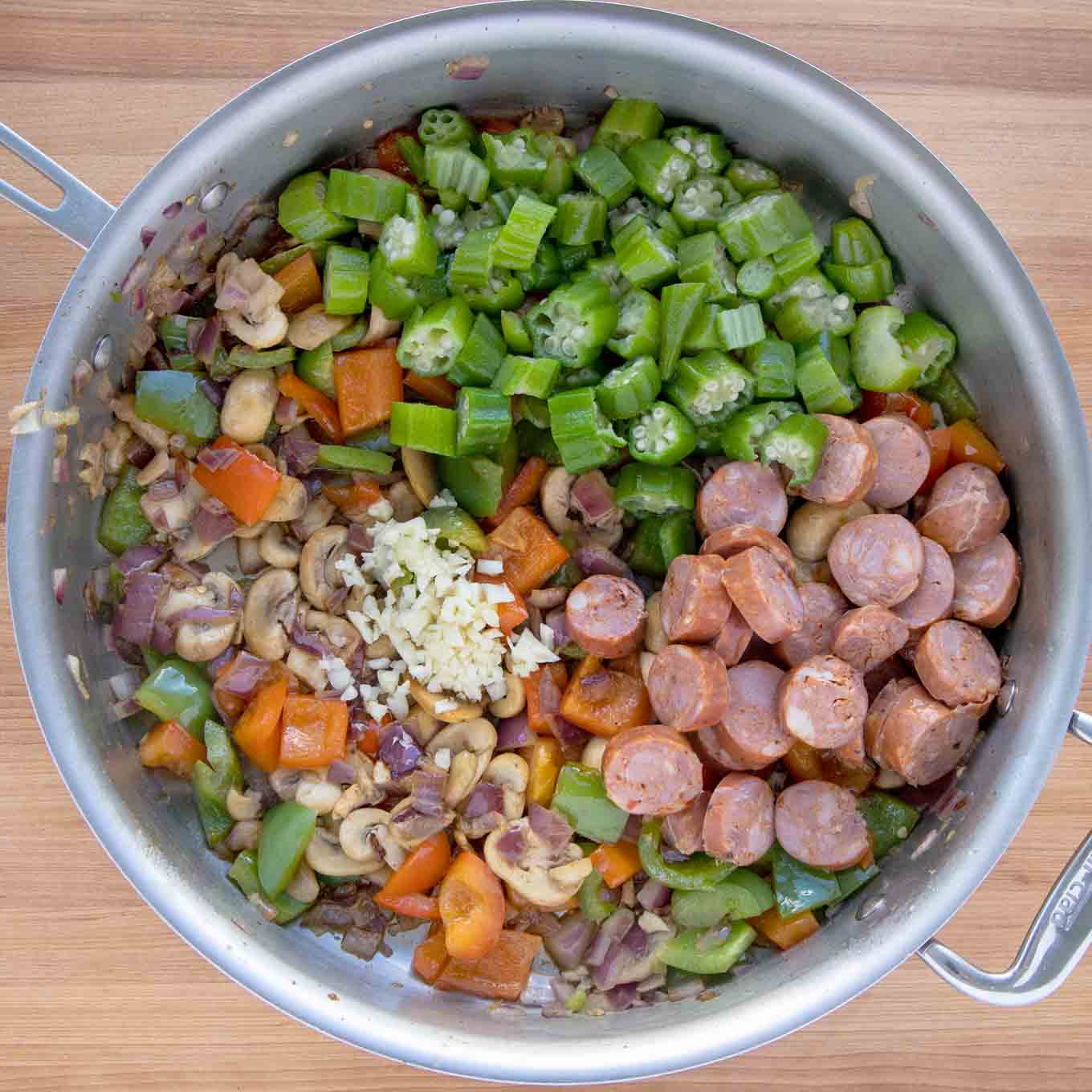 sausage, okra and garlic added to the sauteed vegetables in the skillet