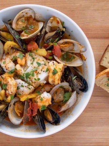 bowl of seafood stew next to garlic toast