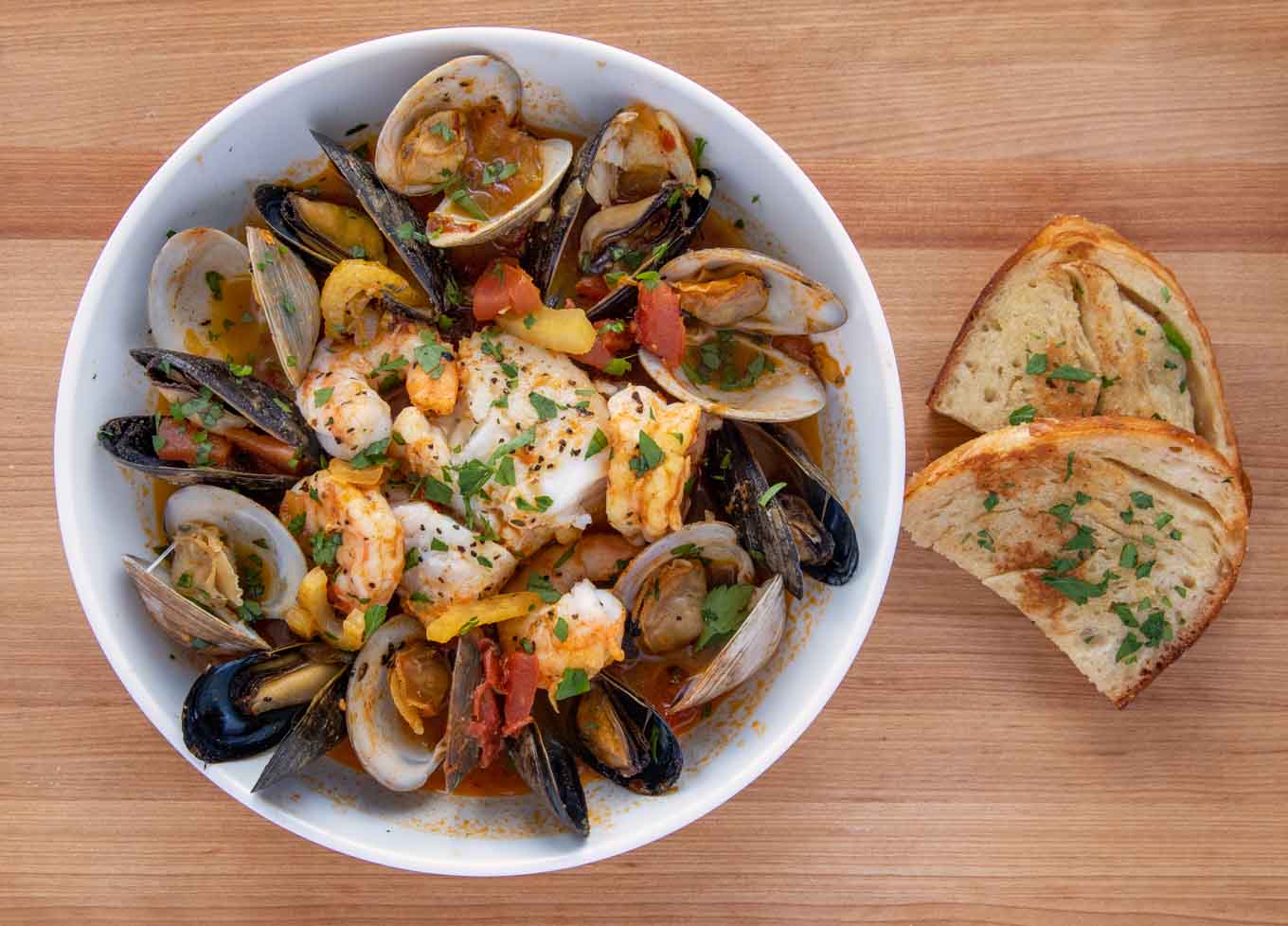 bowl of seafood stew next to garlic toast