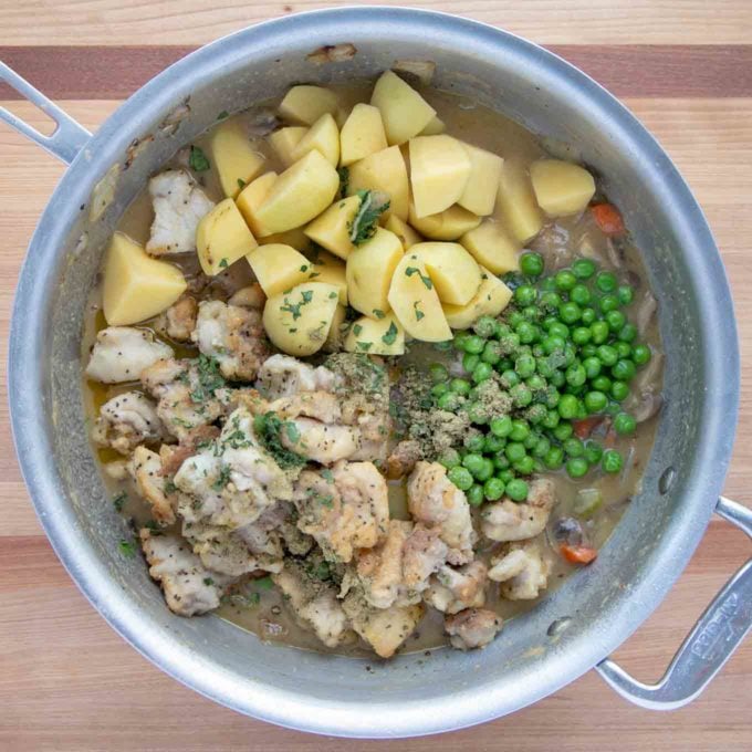 chicken and vegetables added to stew broth in large pan.