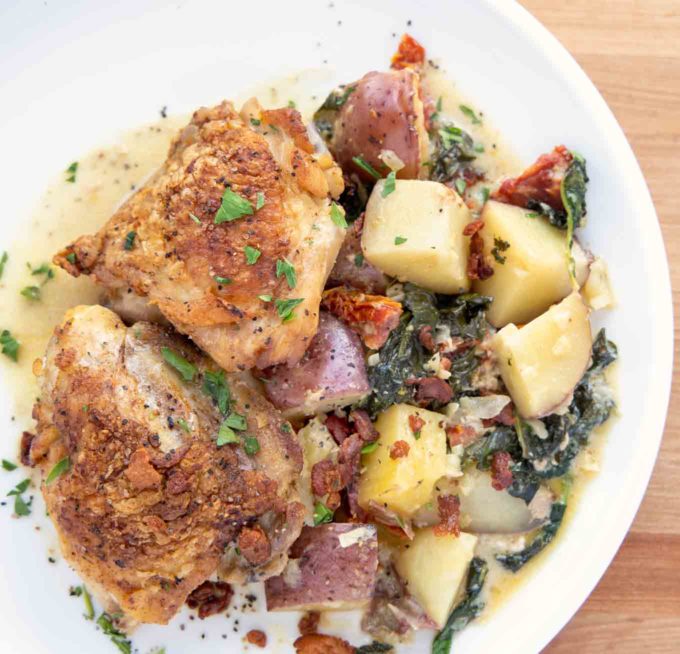 Tuscan Chicken with potatoes on a white plate