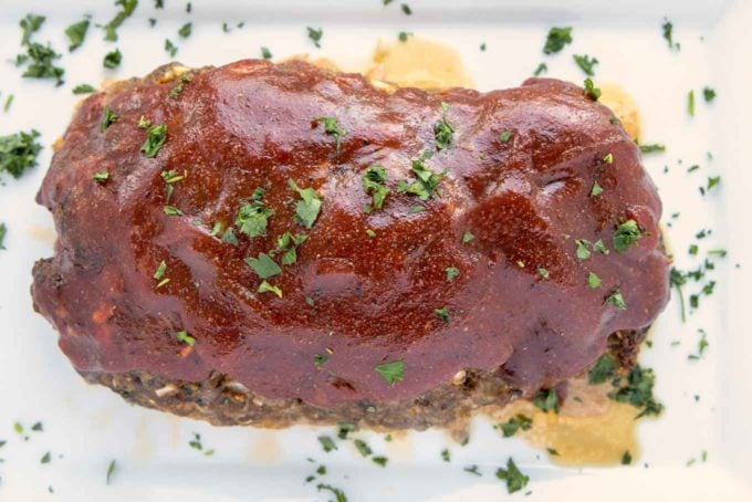 finished meatloaf garnished with chopped parsley on a baking sheet