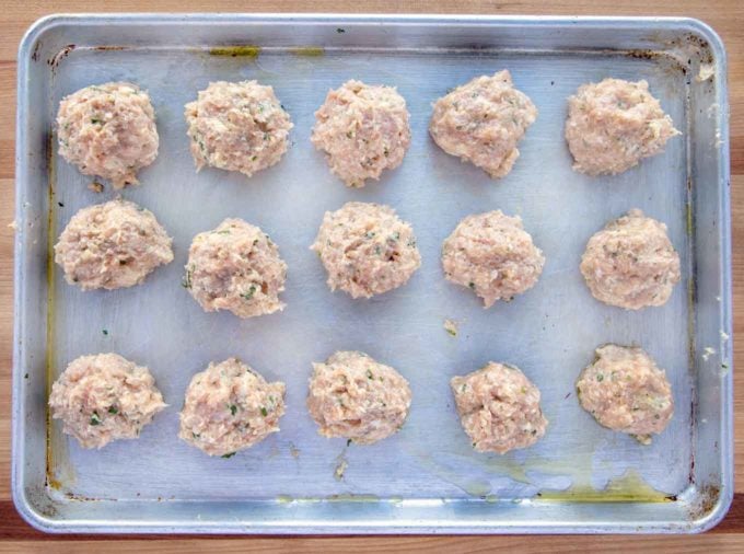 rows of raw meatballs on a sheet pan