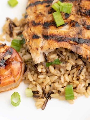 grilled rockfish on a bed of rice next to grilled shrimp on a white plate