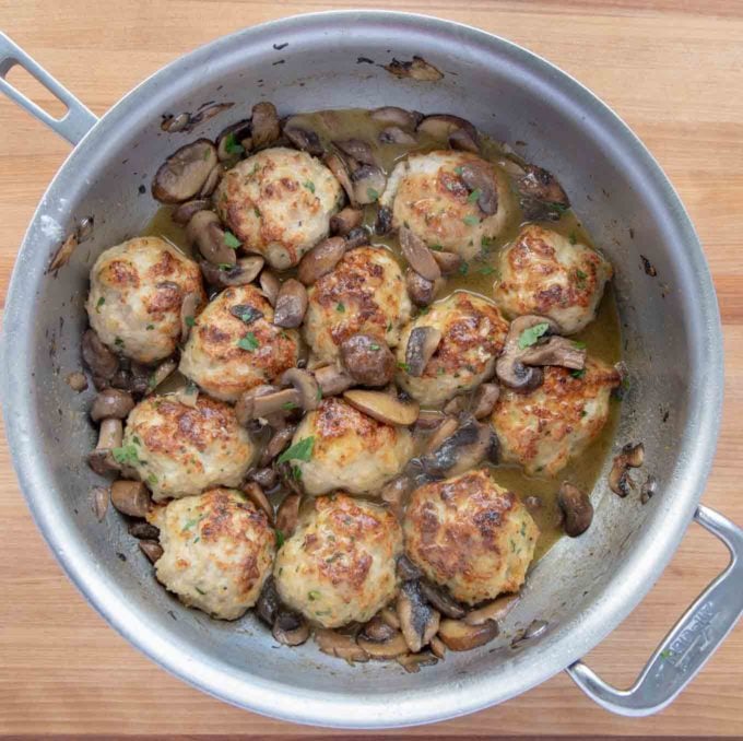 meatballs added to mushroom marsala sauce in a saute pan