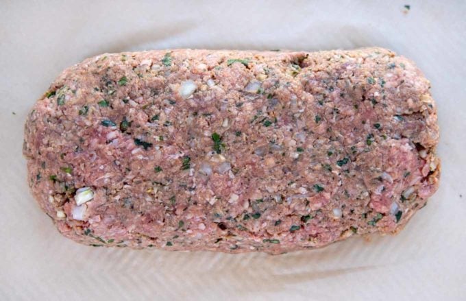 meatloaf mixture shaped into a loaf sitting on a parchment lined baking dish
