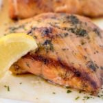 crispy browned Irish whiskey salmon with a lemon wedge on a white platter