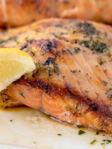 crispy browned Irish whiskey salmon with a lemon wedge on a white platter
