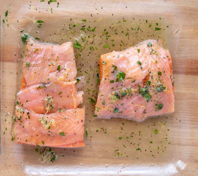 wrapped marinated salmon in glass baking dish with marinade