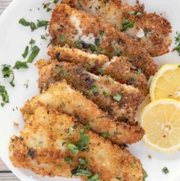fried flounder filets on a white plate with lemon circles