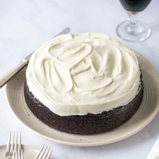 whole frosted guinness chocolate cake with a pint of guinness in the back ground