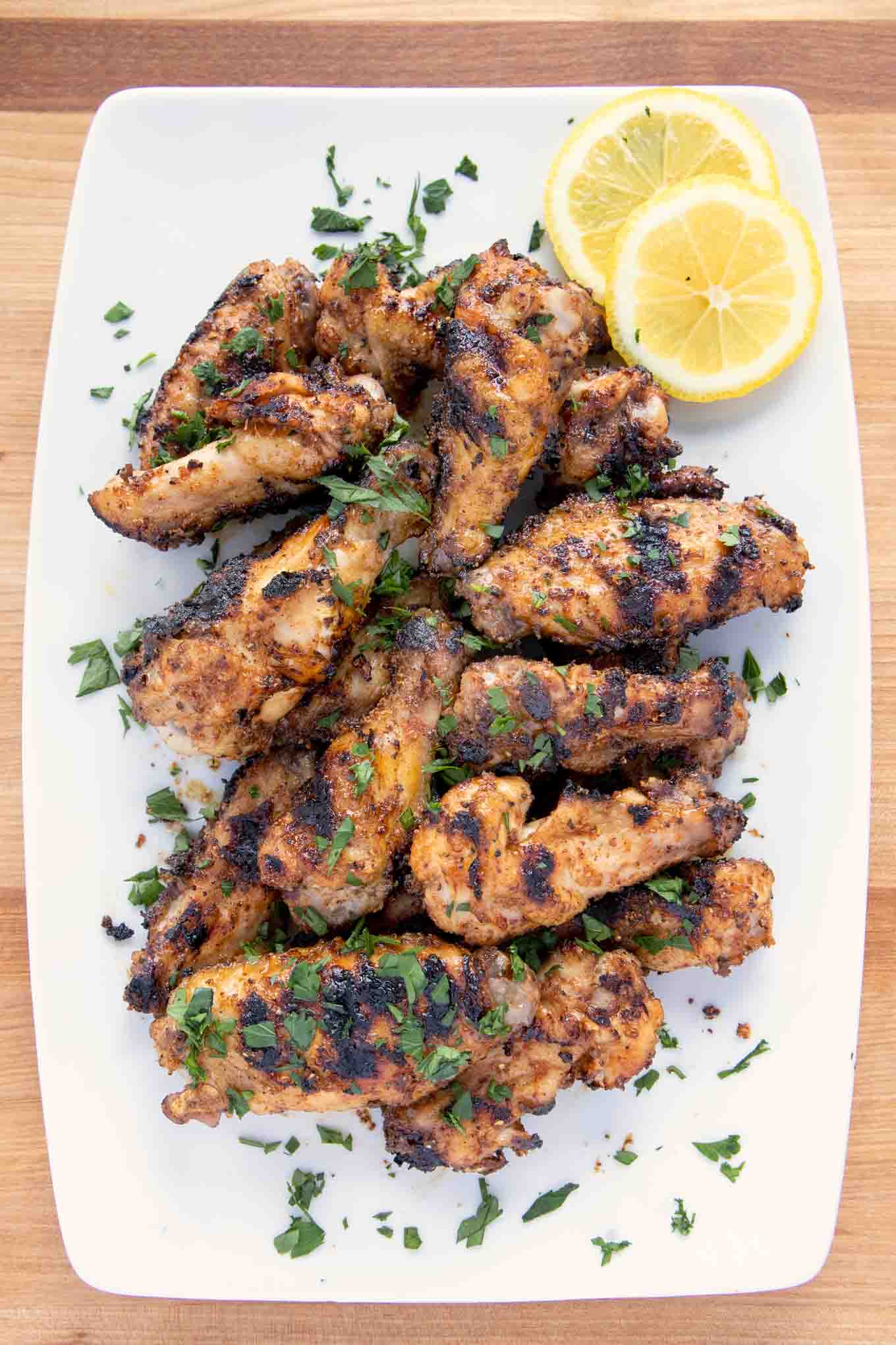 overhead shot of grilled dry rub lemon pepper chicken wings on a white platter