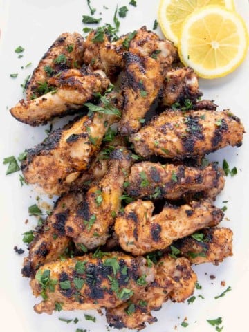 overhead shot of grilled dry rub lemon pepper chicken wings on a white platter