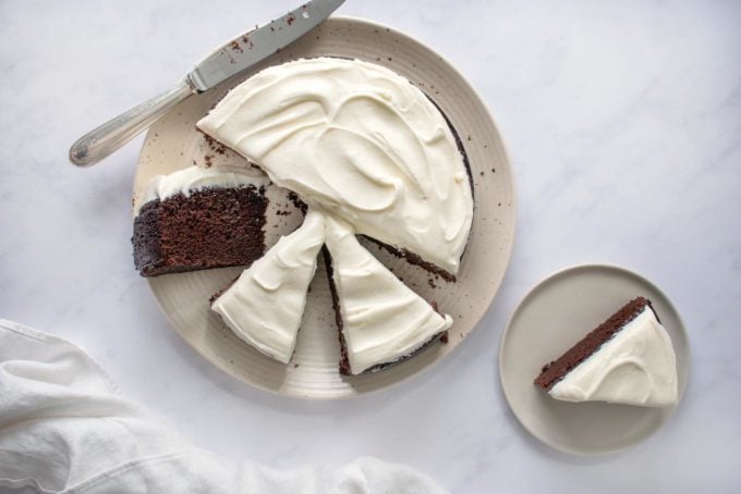 overhead shot of Guinness chocolate cake sliced on a white platter with a slice on a small plate