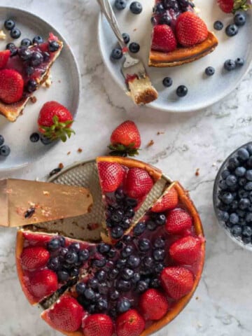 overhead view of sliced cheesecake with slices next to it on plates