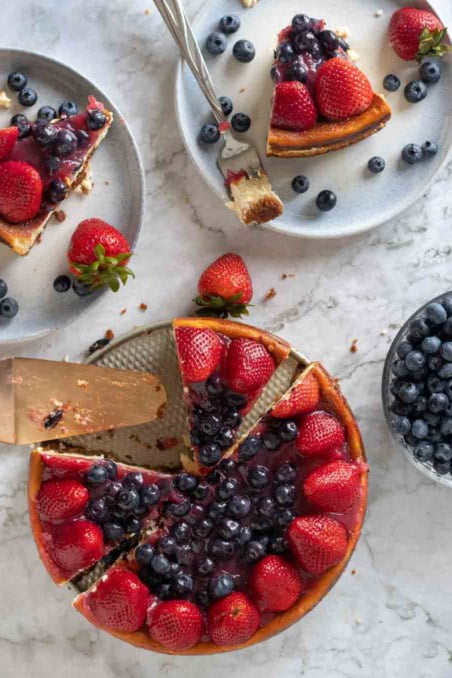 overhead view of sliced cheesecake with slices next to it on plates