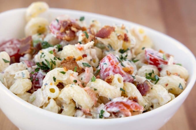 close up view of tuna macaroni salad deluxe in a white bowl
