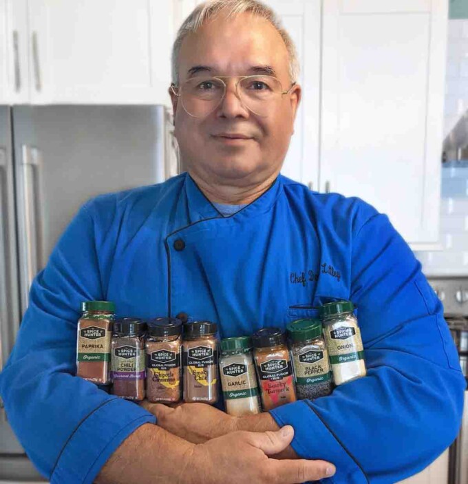 chef dennis in blue chef coat holding 8 jars of spices