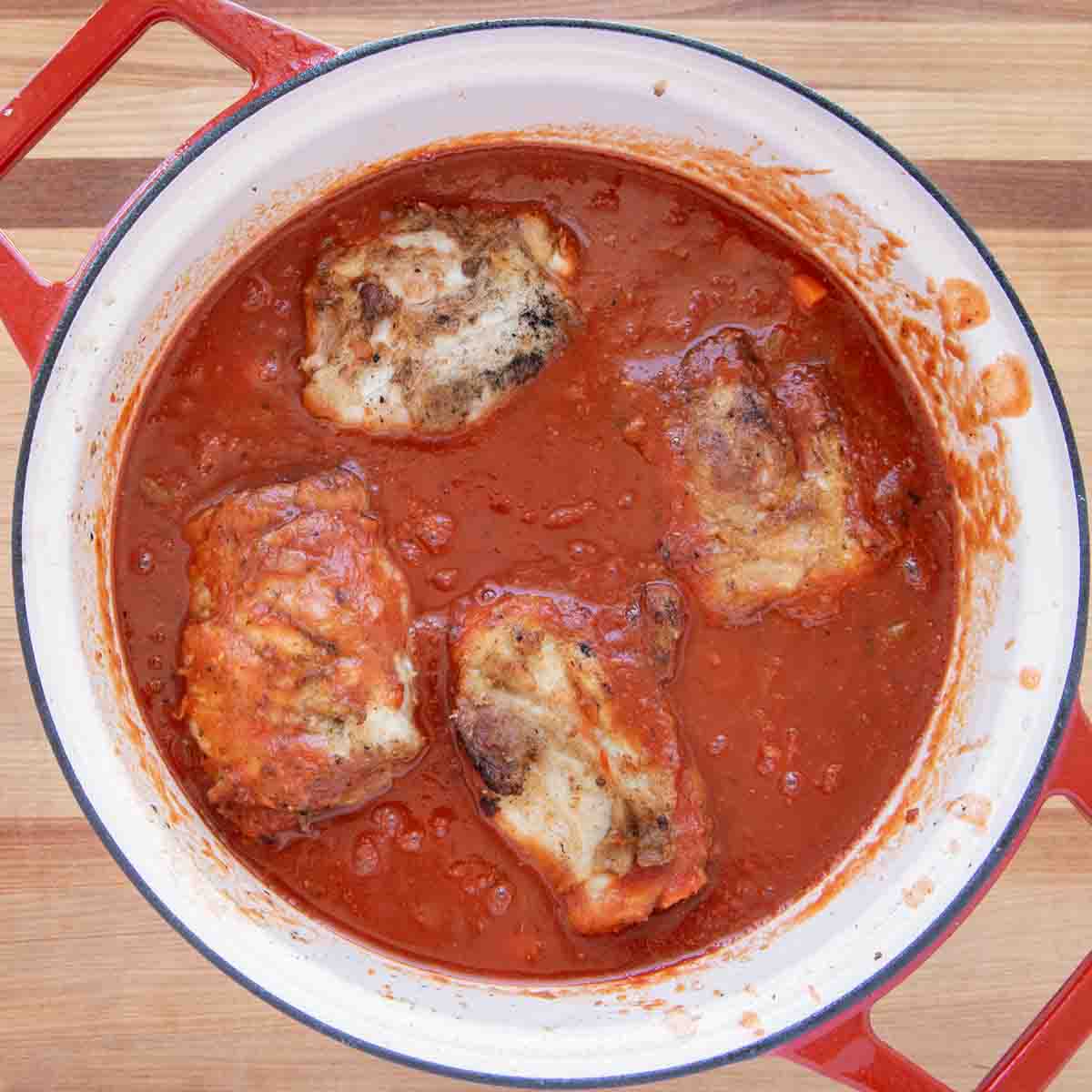 seared pork shanks added back into the pot of tomato sauce