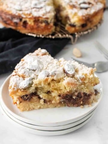 slice of ricotta chocolate chip cake on a stack of white plates