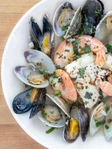 partial overhead view of seafood combo in white bowl