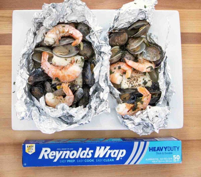 two seafood combo packets open with a box of reynolds foil on the table with them